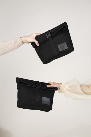 This image shows two hands holding The Usan Utility Pouch against a white background.